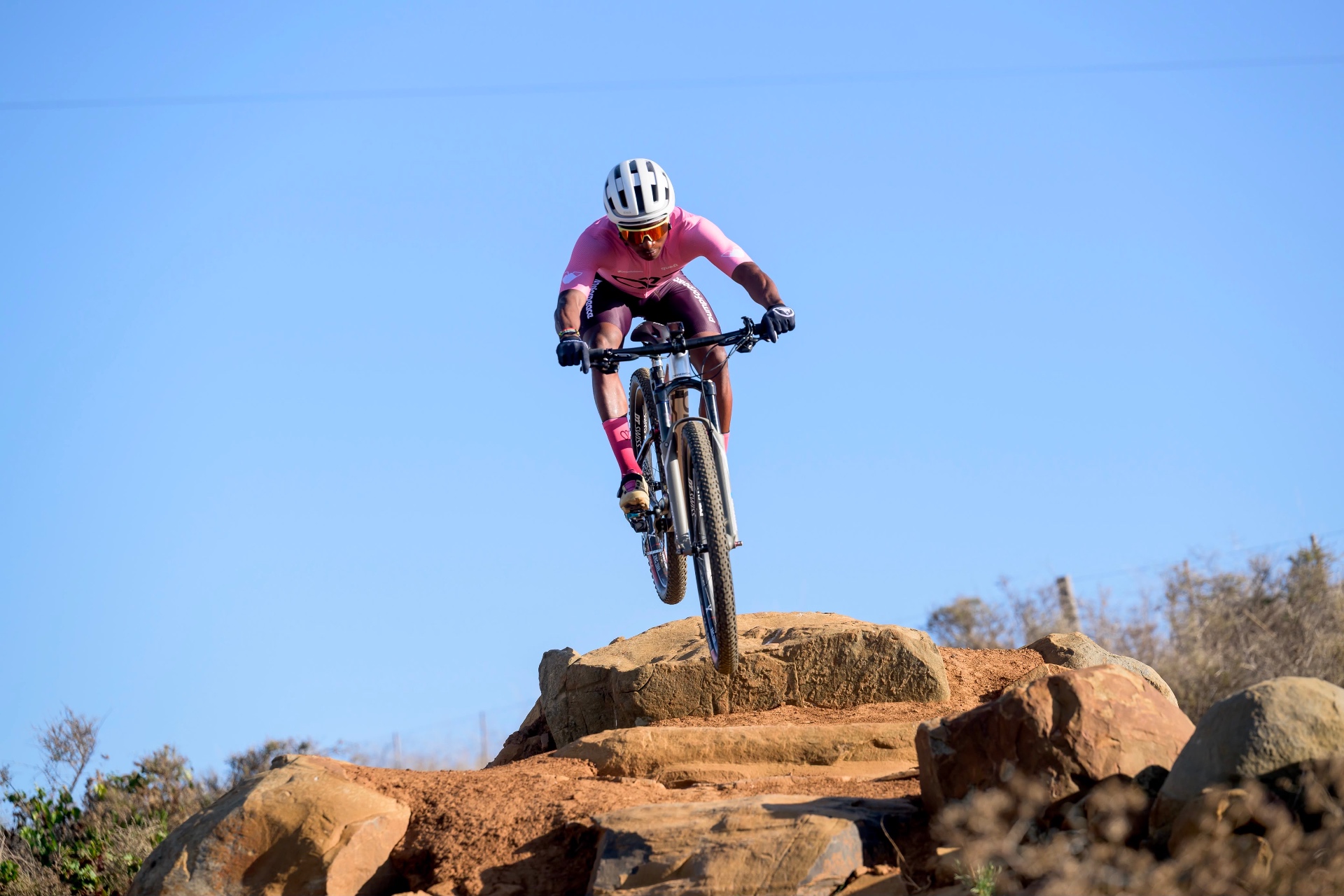 Unathi Nxumalo airborne off a rock drop in pink Pump for Peace kit